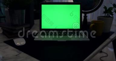 带有绿色屏幕的笔记本电脑。 黑暗的办公室。 多利加入。 完美地放置你自己的图像或视频。 正在使用的技术绿色屏幕。 语文